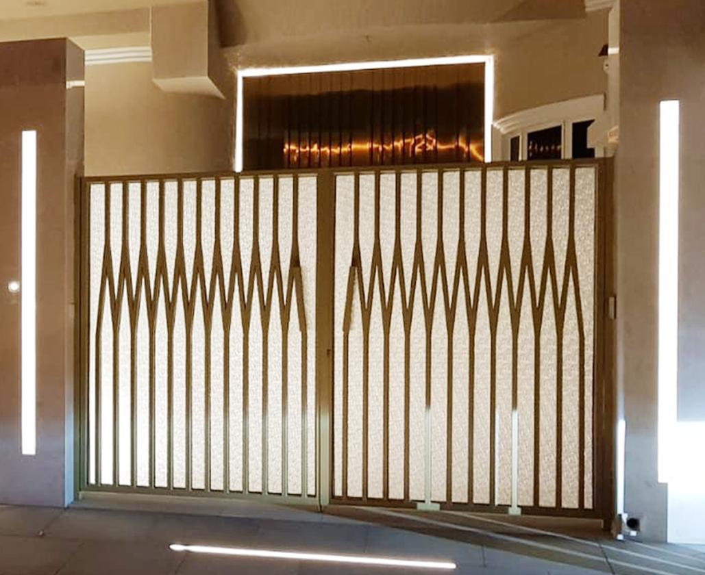 Decorative metal entrance gate with sculpted vertical bars and backlit screen